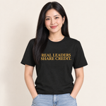 Frau trägt das T-Shirt „Real Leaders Share Credit.“ in Schwarz