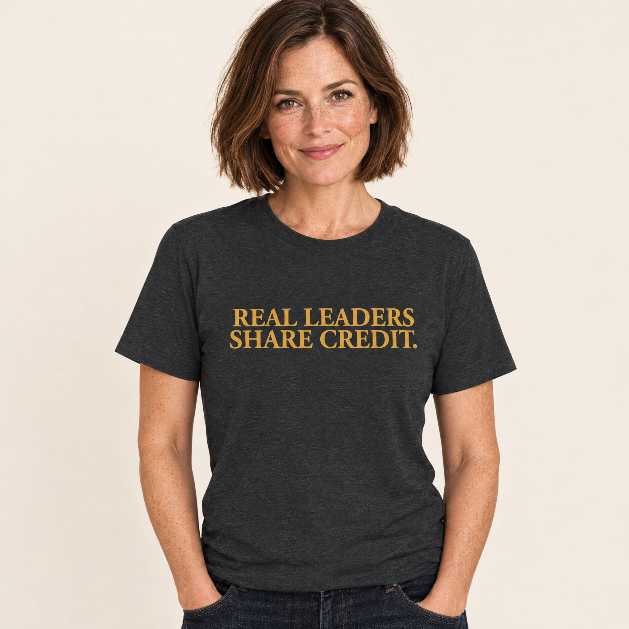 Frau trägt das T-Shirt „Real Leaders Share Credit.“ in Dark Heather Grey