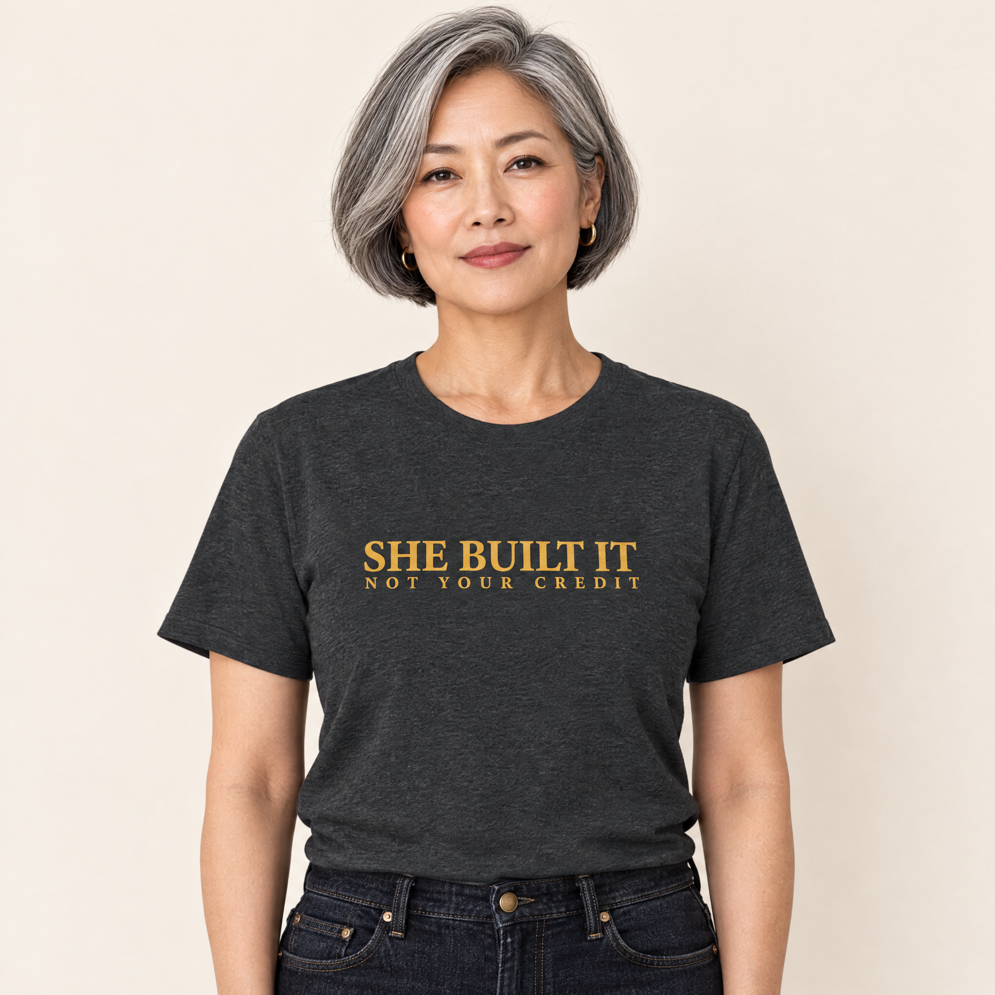Frau trägt das T-Shirt „She Built It – Not Your Credit“ in Dark Heather Grey
